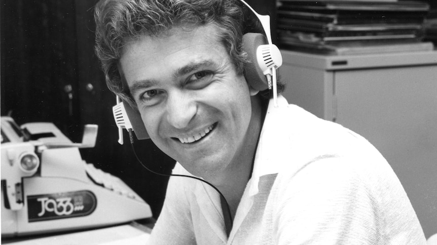 Stephen Watkins wearing headphones and smiling at the camera.