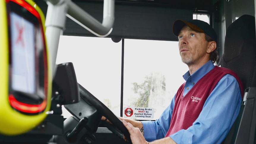 Brett Crutchfield sits in the drivers seat of his bus. He looks in the rear vision mirror to make sure his passengers are safe.