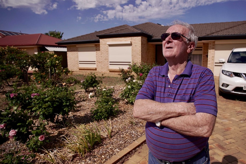 John Paynter standing with his arms crossed in his front yard.