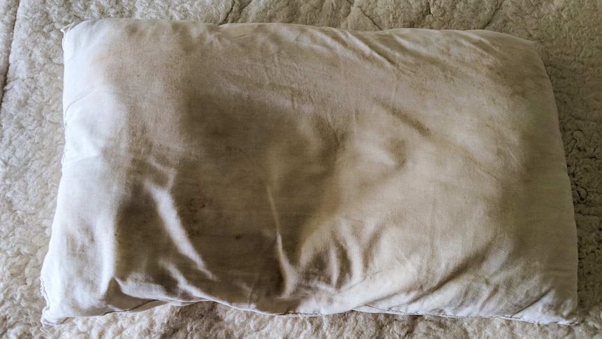 Dirty pillow on bed for story about how often you should replace your pillows and mattresses