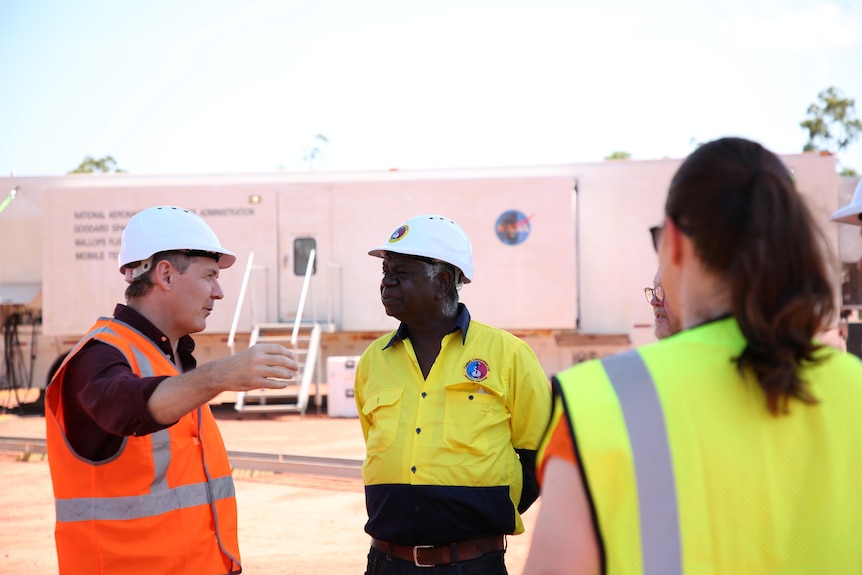 An Indigenous man in conversation with the Chief Minister and a woman wearing hi-vis