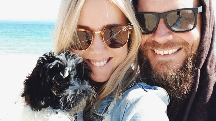 Kellie takes a selfie with Peppa and Travis on the beach to depict surviving the week with a new pet puppy.