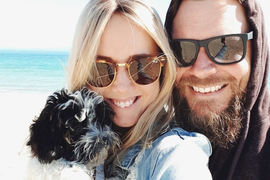 Kellie takes a selfie with Peppa and Travis on the beach to depict surviving the week with a new pet puppy.