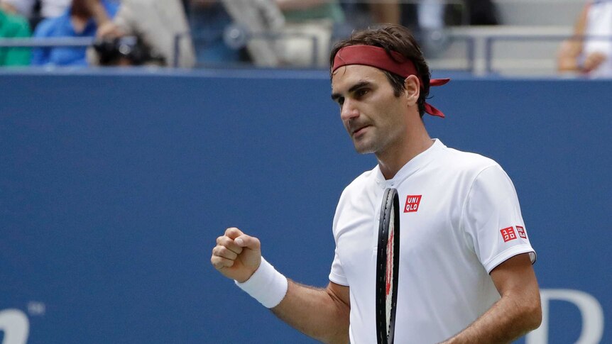 A male tennis player wearing a white shirt and red headband clenches his fist.