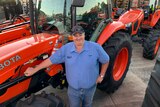 A man standing in front of red tractors smiling. 