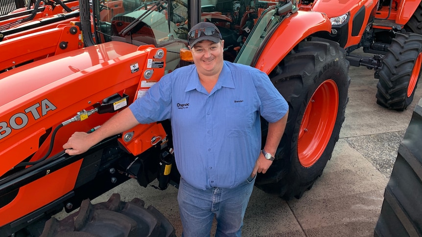 A man standing in front of red tractors smiling. 