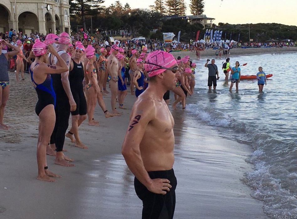 Nadadores com toucas cor-de-rosa ao longo da costa de Cottesloe Beach.