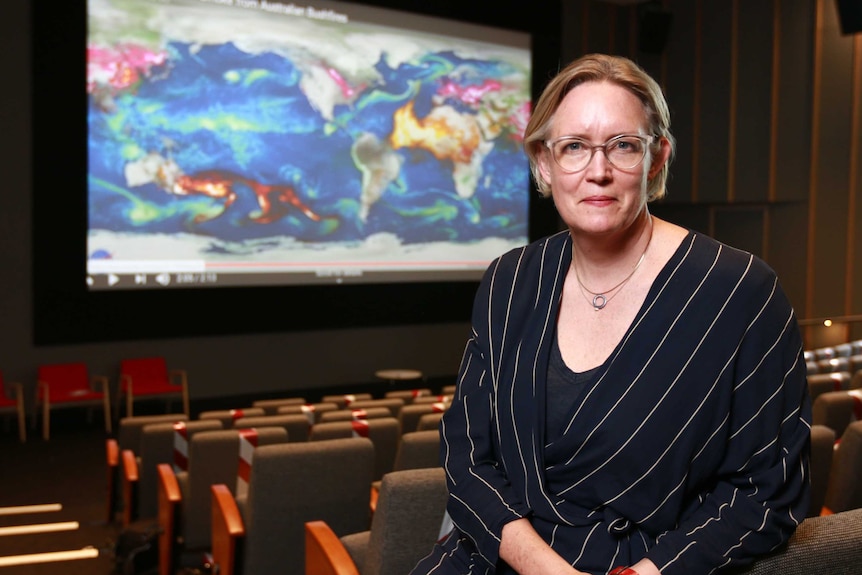 A woman in a suit with a map in the background