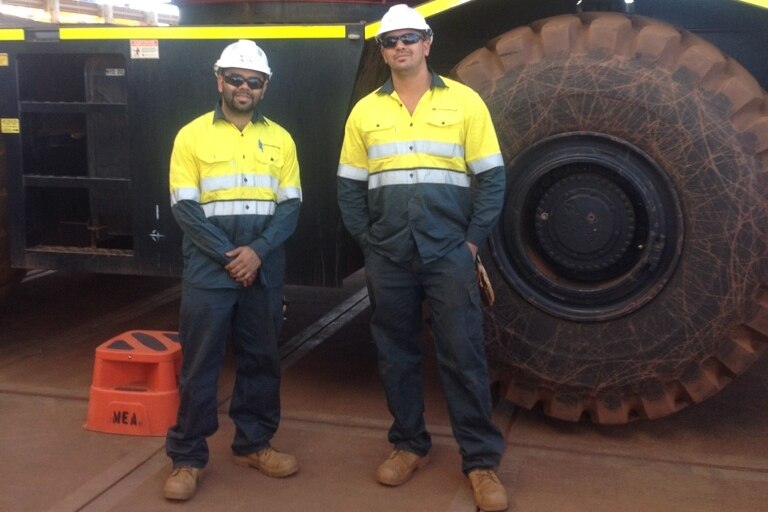 Workers from the Pathways to the Pilbara program stand next to mining trucks.