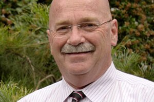 bald man with moustache and glasses smiling at the camera