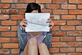 A woman holds up a 'Victim' sign.