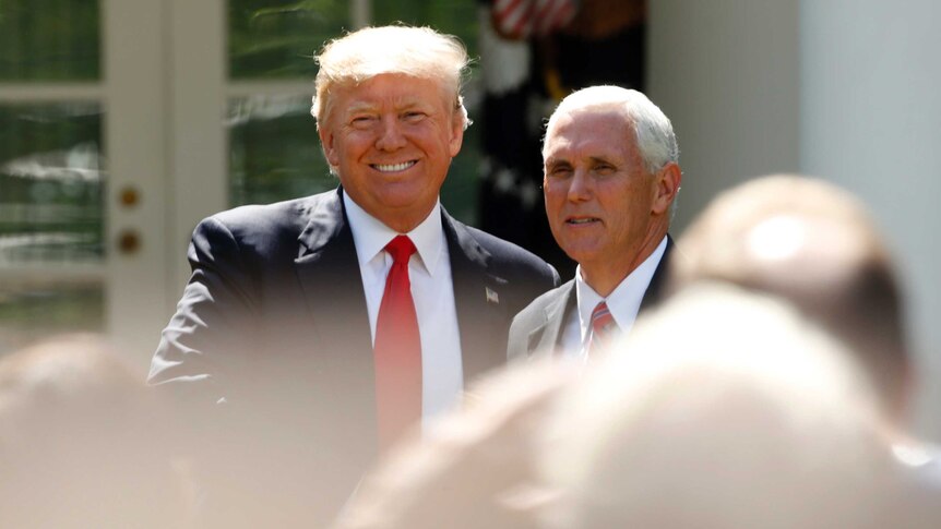Donald Trump smiles as he stands next to Mike Pence outside the White House.
