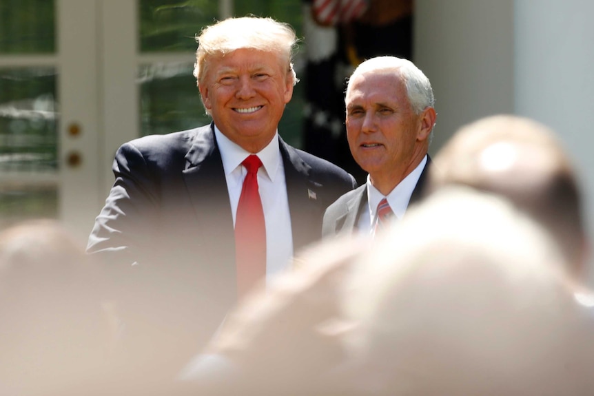 Donald Trump smiles as he stands next to Mike Pence outside the White House.