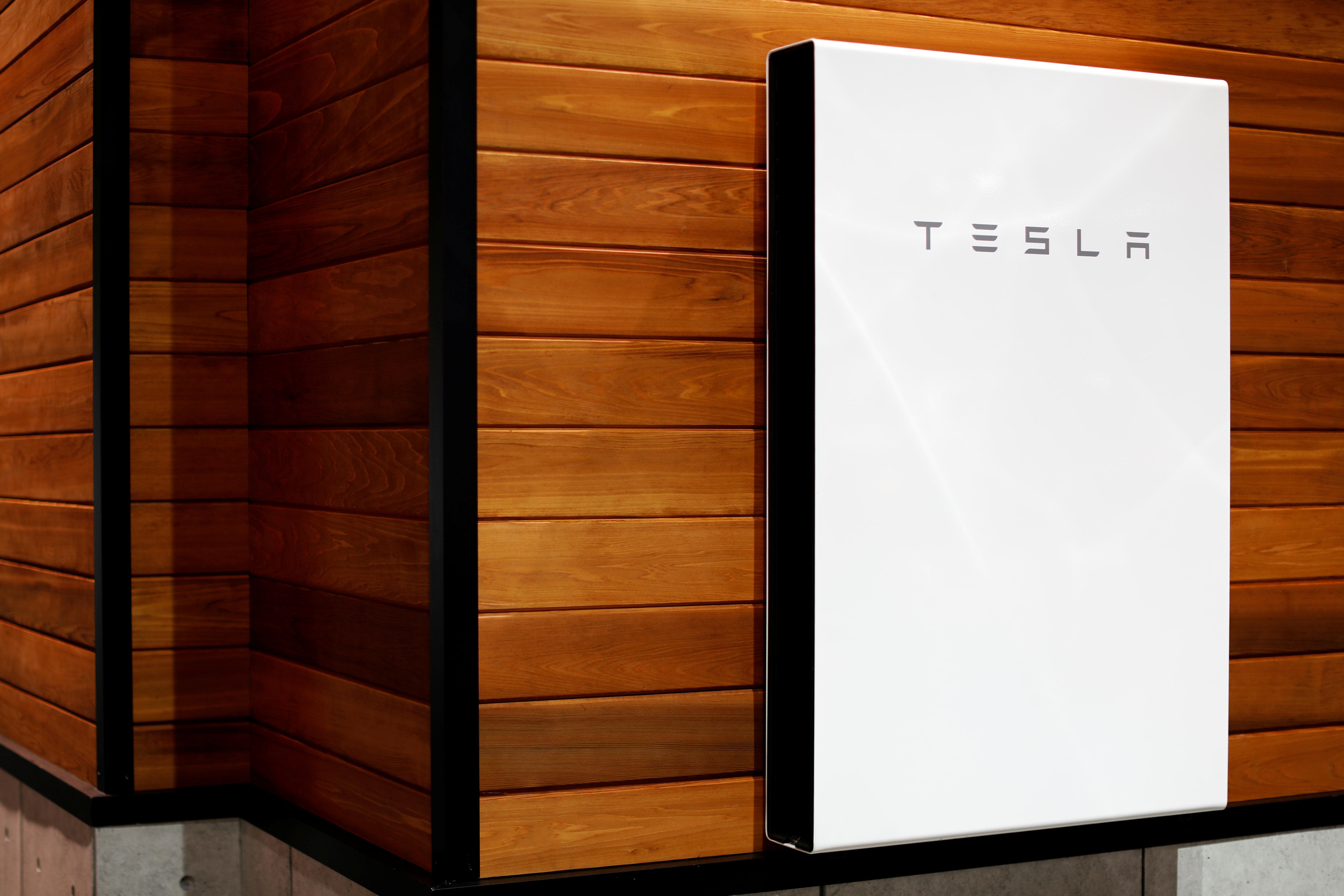 White box of a battery with the Tesla logo, fitted to a wooden wall