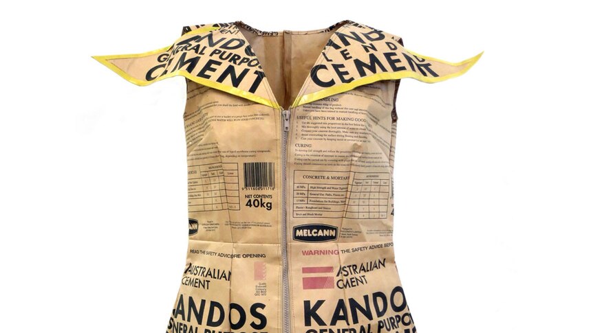 A woman's dress with a big collar and a zip up the front made from brown paper printed with Kandos Cement