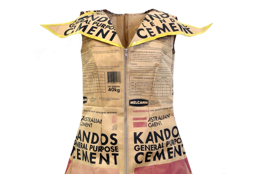 A woman's dress with a big collar and a zip up the front made from brown paper printed with Kandos Cement