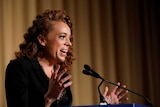 Comedian Michelle Wolf speaking at a podium.