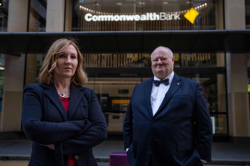 a woman and a man in a bowtie stand outside a building with a logo reading Commonwealth Bank