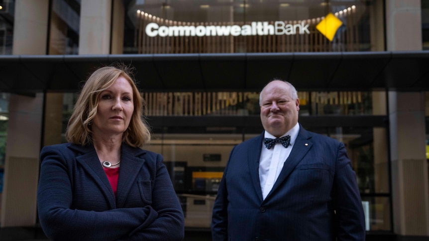 a woman and a man in a bowtie stand outside a building with a logo reading Commonwealth Bank