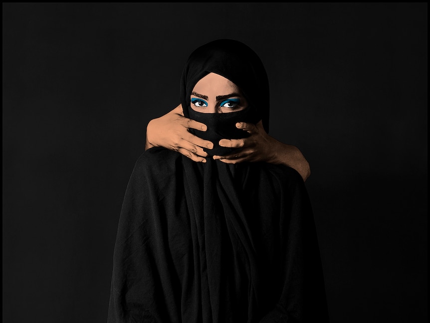 pop art photo of a muslim women in a black scarf with someone's hands around her mouth.