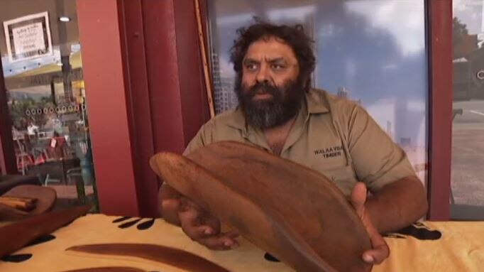 Indigenous artist Darryl Ferguson holding a traditional coolamon he made