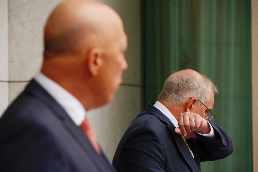Scott Morrison coughs into his elbow while at a press conference with Peter Dutton