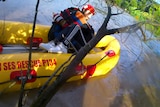 ses personnel holds a woman in a boat as he rescues her from flood water