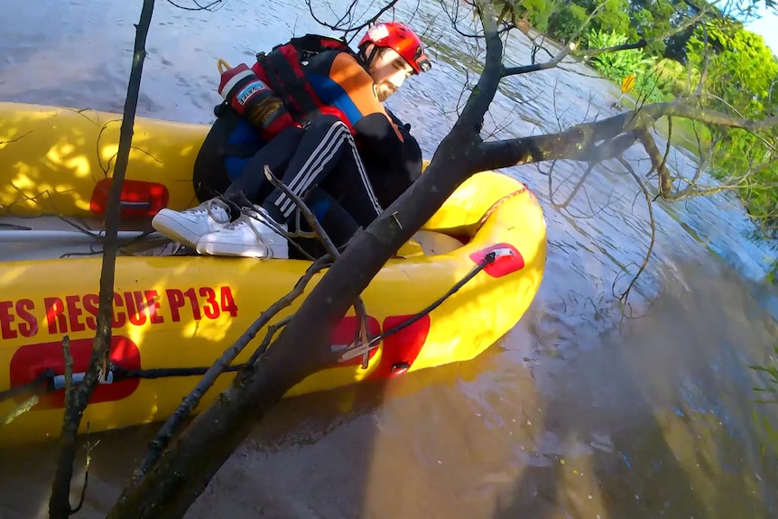 ses personnel holds a woman in a boat as he rescues her from flood water