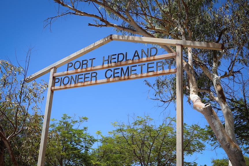 A tall arched sign reads 'Port Hedland Pioneer Cemetery' with trees around 