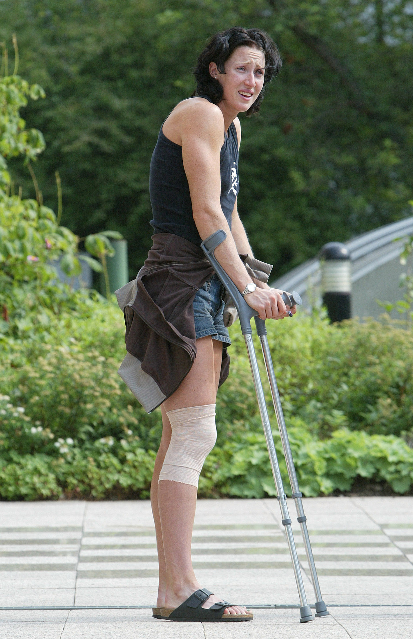 Jana Pittman, with bandaged knee and holding crutches, stands with brow furrowed.