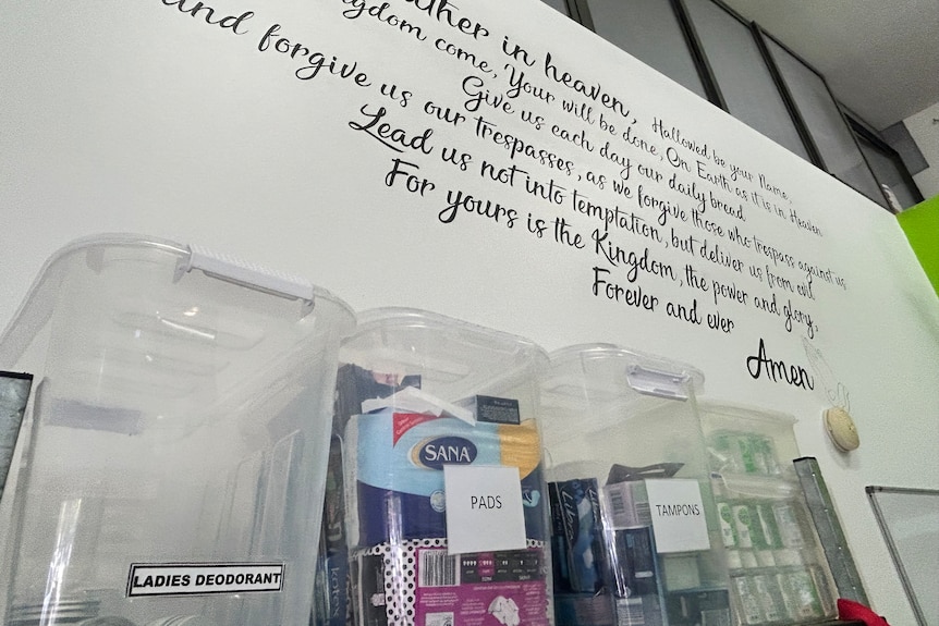 Prayer on wall with boxes of goods in foreground