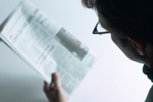 An unidentifiable person reads an unidentifiable newspaper. (Thinkstock: Hemera)