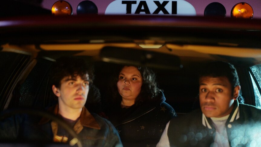 Two men and a woman sit inside a taxi.