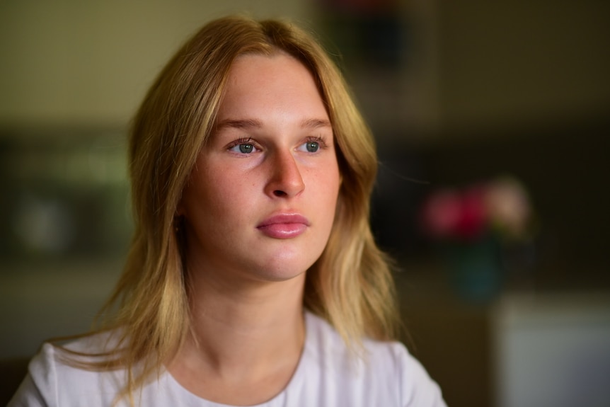 A young woman looks off to the side, her expression is neutral