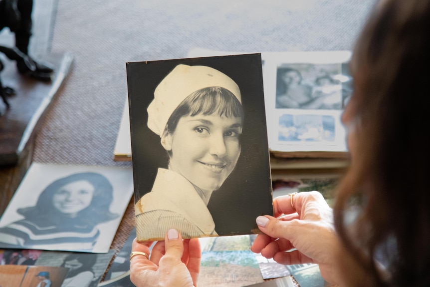 Black and white woman of a female nurse being held by a woman  who is looking at photo albums