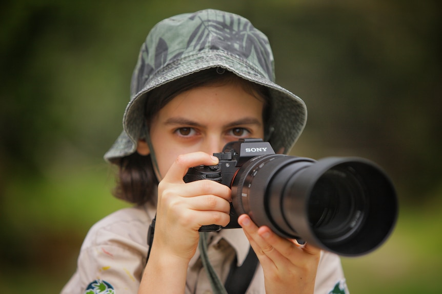 A boy holds a camera to his face