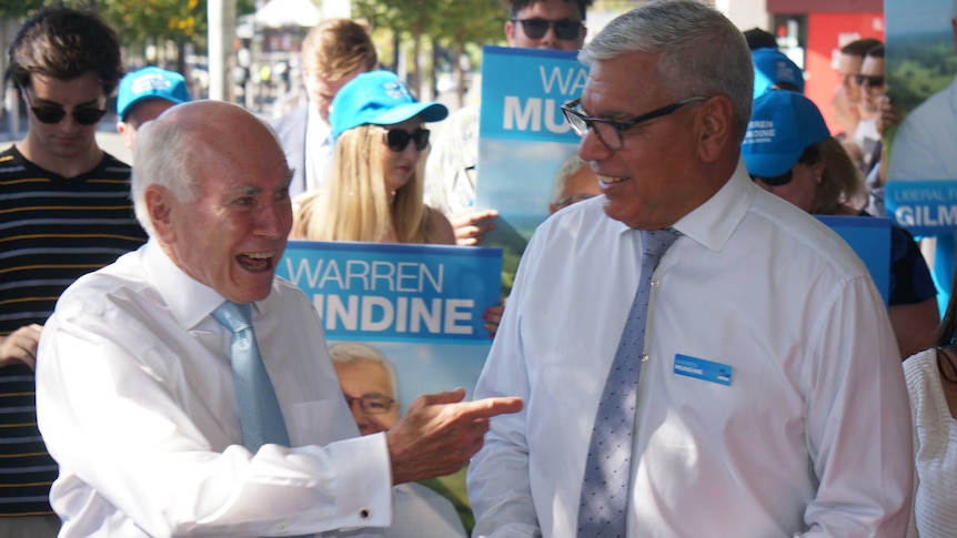 Former PM John Howard smiles and points at the Liberal Party's Gilmore candidate, Warren Mundine.