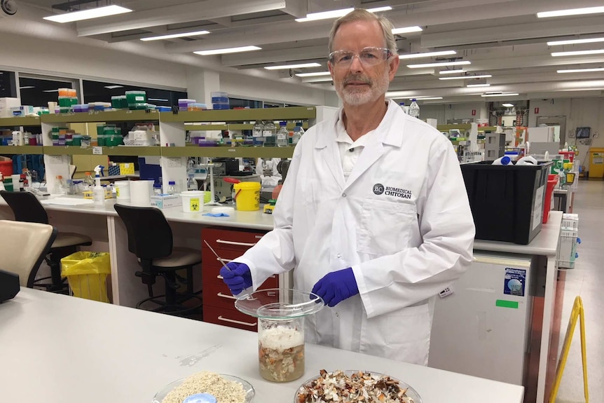 David Hewitt standing in a lab with bowl of prawn shells.