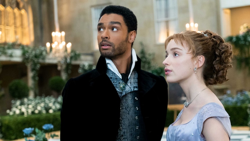 Still from the Netflix regency romance series Bridgerton with Rege-Jean Page and Phoebe Dynevor at a fancy event
