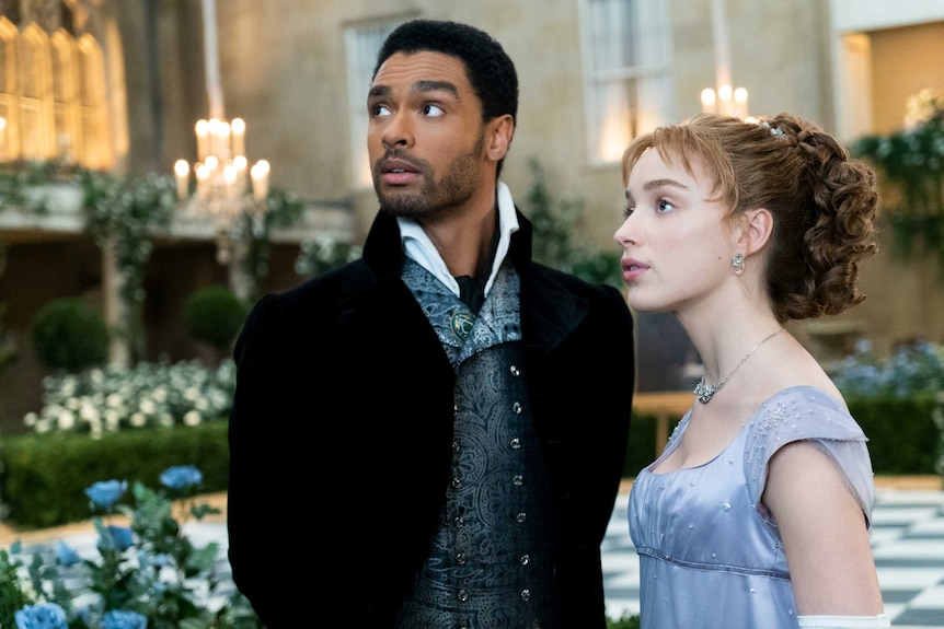 Still from the Netflix regency romance series Bridgerton with Rege-Jean Page and Phoebe Dynevor at a fancy event