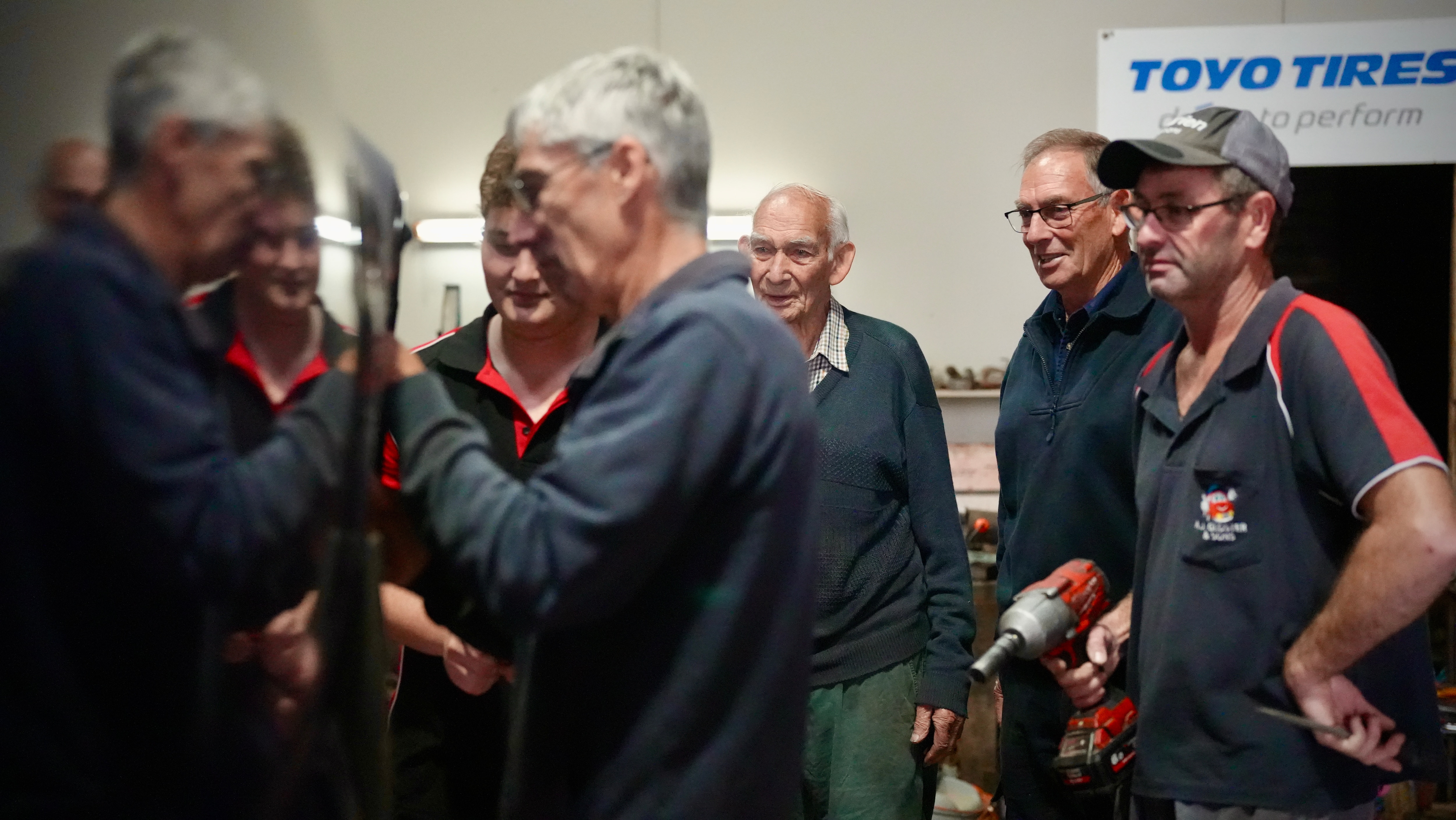 Cinco hombres se paran al costado del vagón levantado y trabajan para mantenerlo.