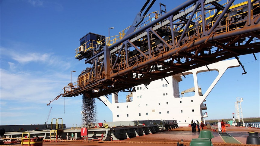 Iron ore is loaded into a cargo ship for transport to China
