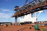 Iron ore is loaded into a cargo ship for transport to China