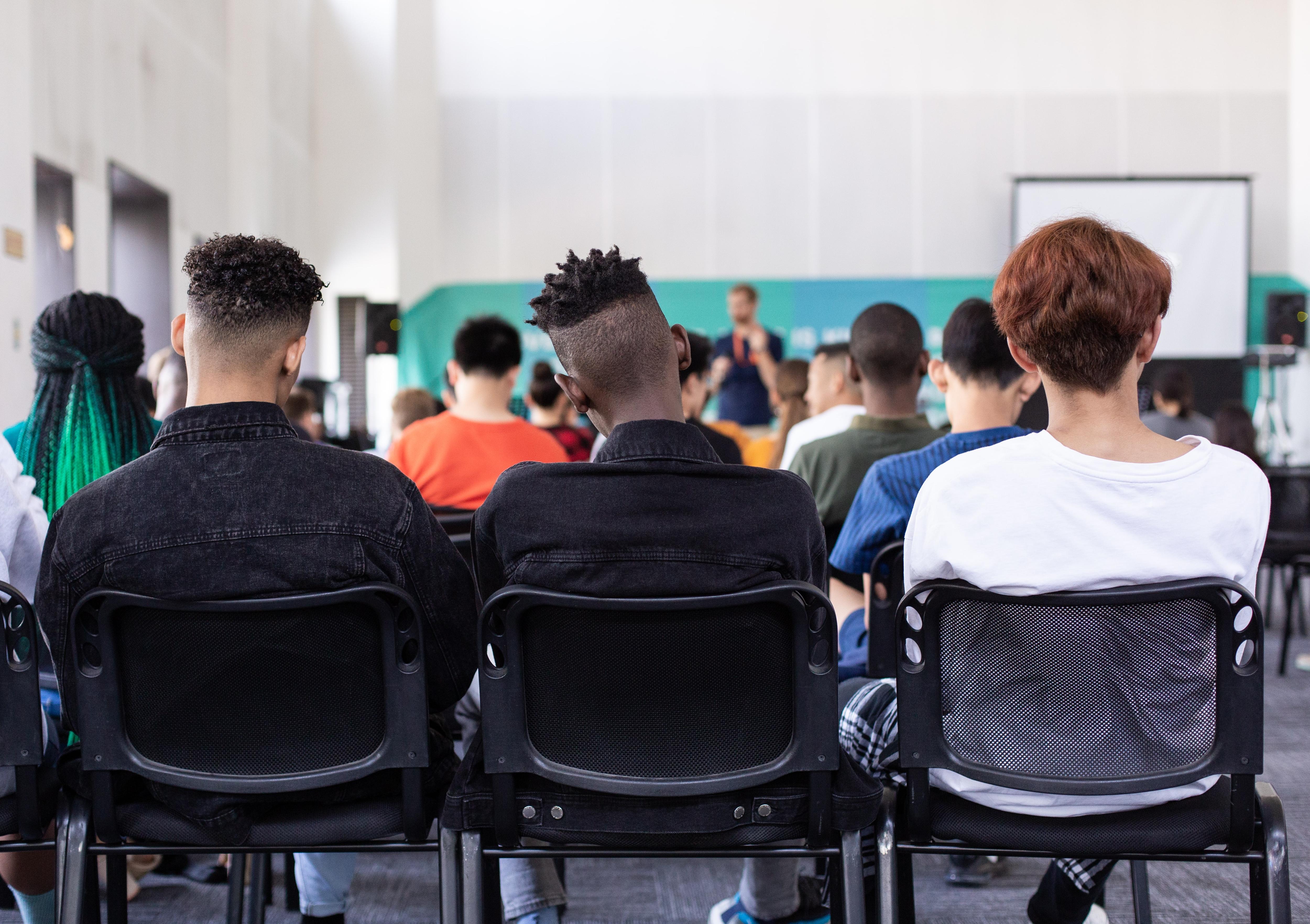 A group of seated students from behind.