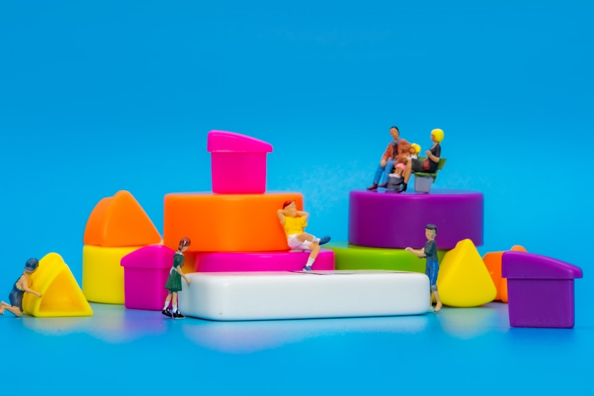 A photo of miniature people playing with blocks.