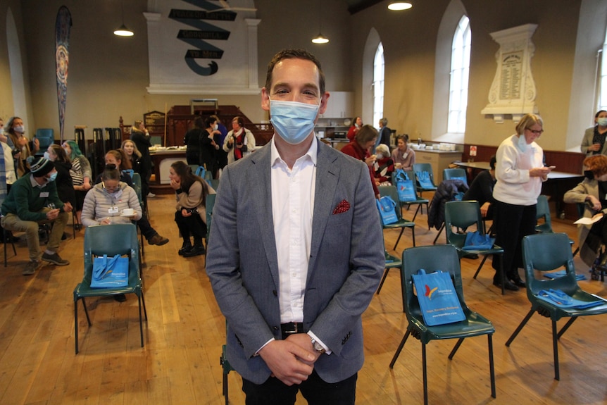 man in suit with mask standing in front of group of people 