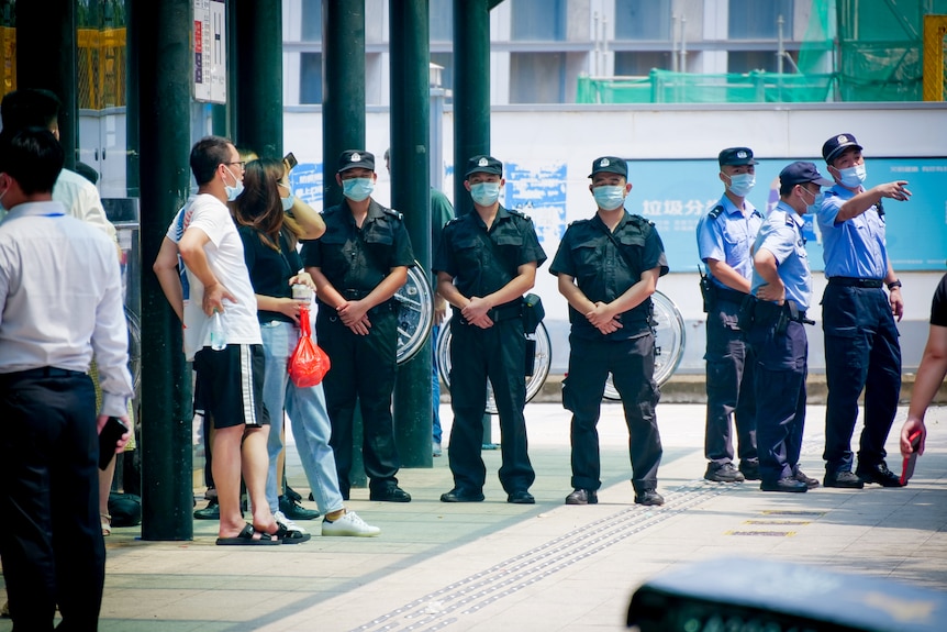 A row of police officers in face masks standing at a building's entrance