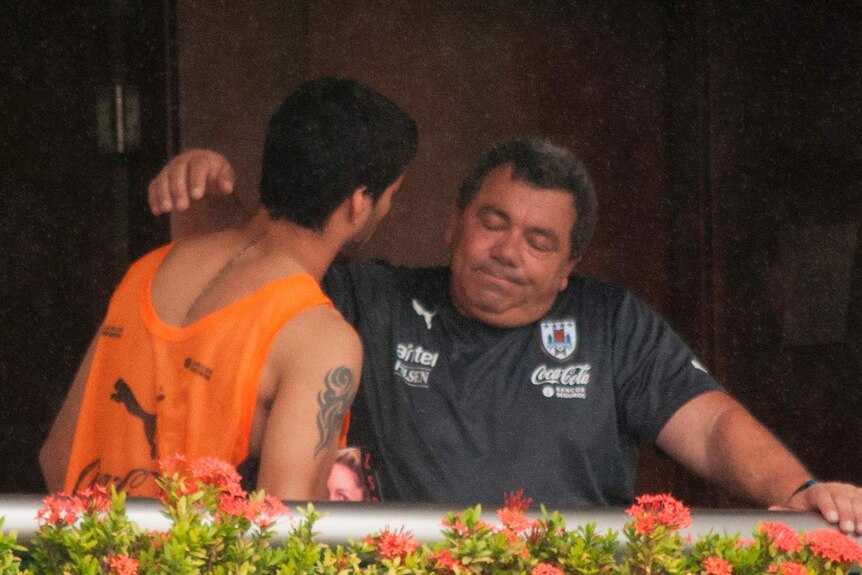 Luis Suarez consoled by team official after being banned for biting