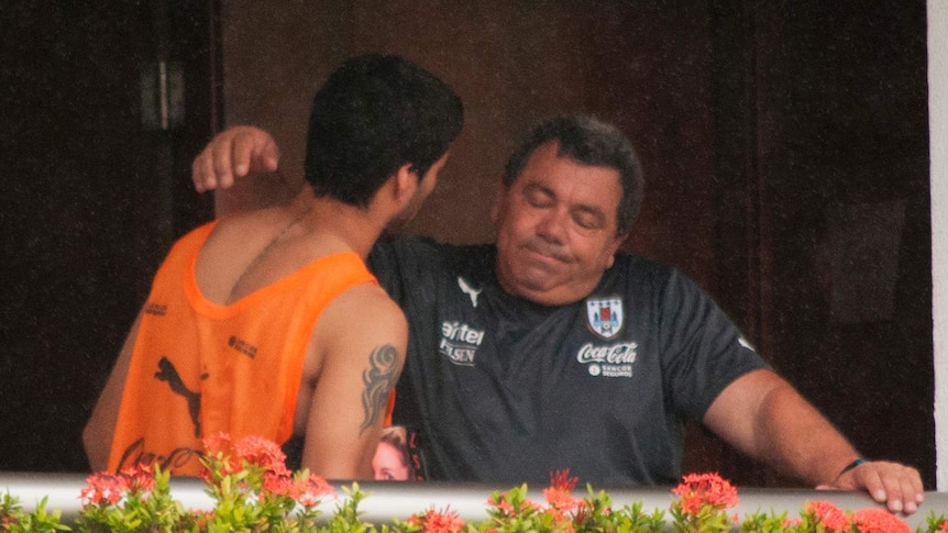 Luis Suarez consoled by team official after being banned for biting