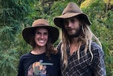 A couple stand in front of a hemp plantation smiling 